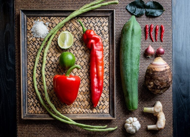 Flat lay of Thai cooking ingredients with chilli peppers, lime, garlic, broadbeans, rice, onion