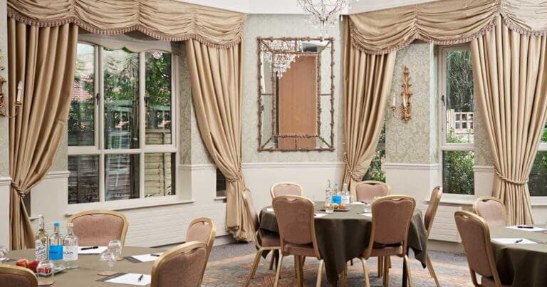 Room set up for a conference with round tables including bottles of water and apples