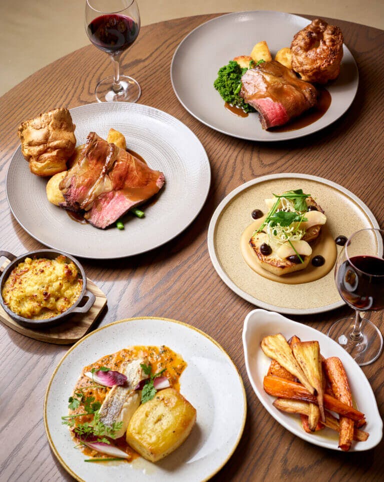 Birds eye view of Sunday lunch dishes on wooden table at Cambium restaurant in Careys Manor Hotel, Brockenhurst