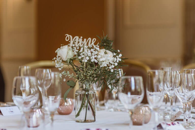 Table set for wedding breakfast with vase of flowers in the centre