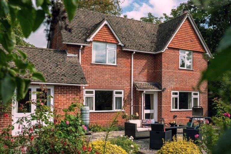 View of cottage through trees with outdoor seating and BBQ