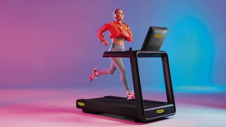 Woman working out using Technogym equipment - treadmill on colourful background
