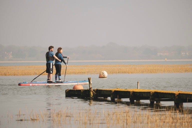 A couple paddle boarding in the New Forest.