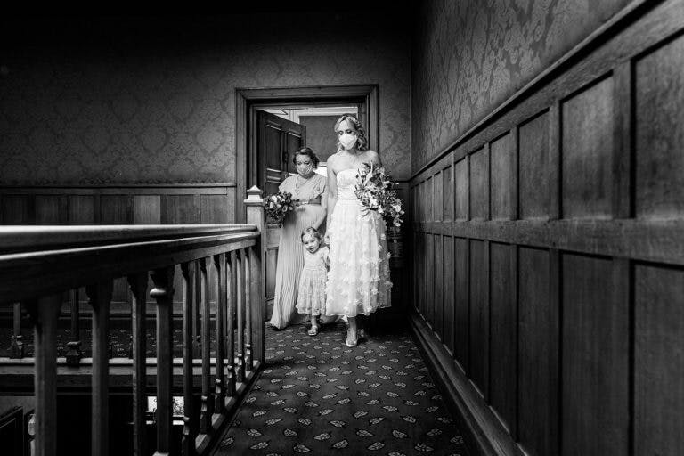 Bride and bridesmaids walking down to a wedding ceremony at Careys Manor Hotel