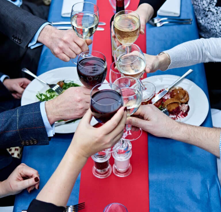 Group cheers with red and white wine glasses at Le Blaireau Restaurant, Brockenhurst