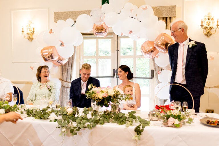 The guests at the top table including the bride and groom laughing during the Father of the brides speech at New Forest Wedding venue Careys Manor Hotel