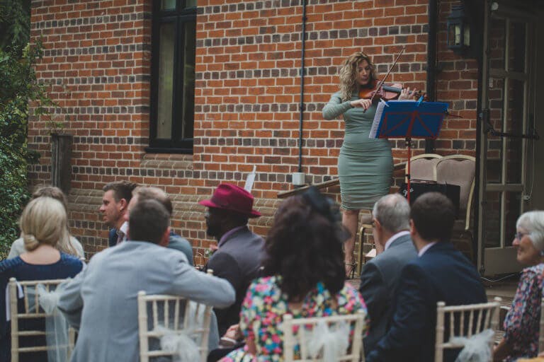Violinist plays to guests during the wedding ceremony at Hampshire wedding venue Careys Manor Hotel