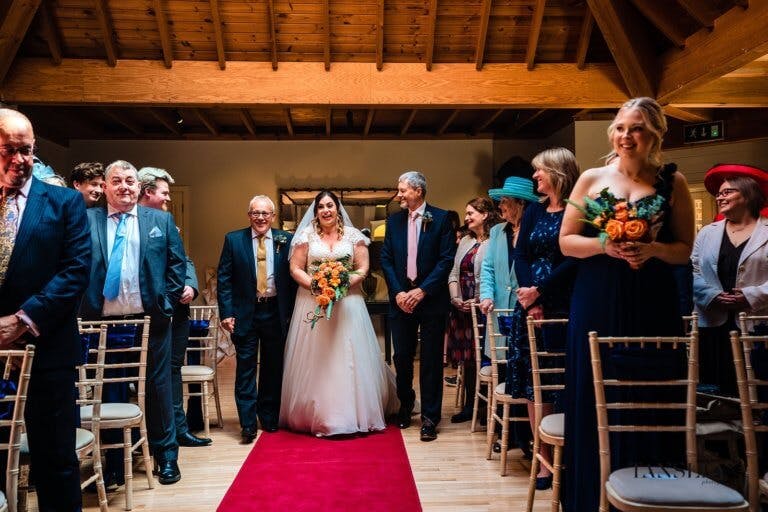 The Bride, her Father and Step Father walk down the aisle of the ceremony