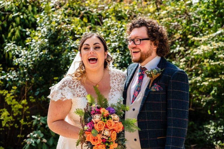 The Bride and Groom smile together for a photo in the gardens