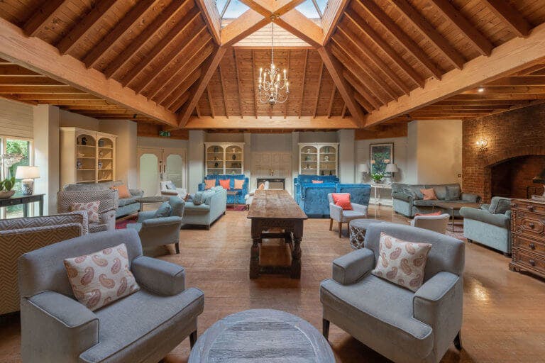 Lounge room in hotel with wood panelled ceiling and multiple armchairs and sofas