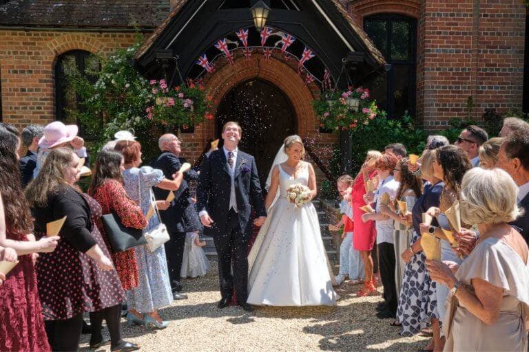 The Bride and Groom leave the main entrance with confetti being thrown
