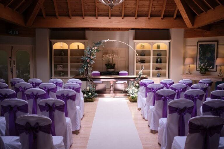 Hotel lounge dressed for a wedding ceremony with a white carpet and floral arch