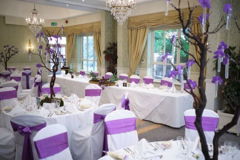 Manor suite set for wedding breakfast with purple flowers and chair sashes