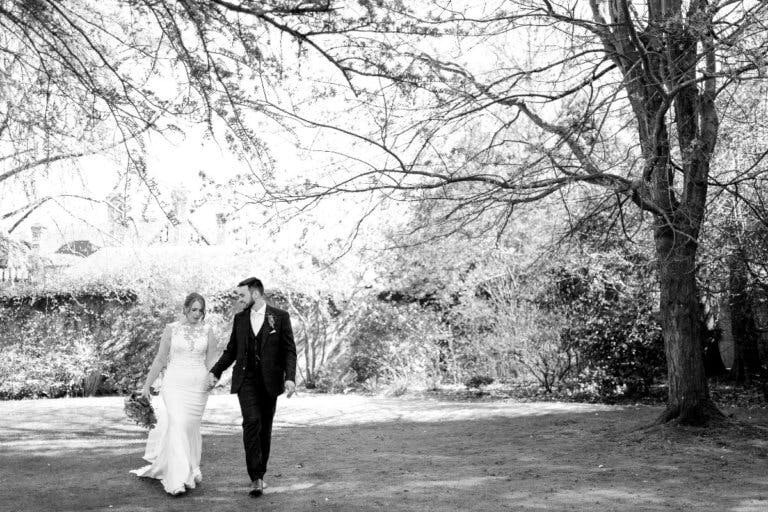 The bride and groom stroll hand in hand in the garden