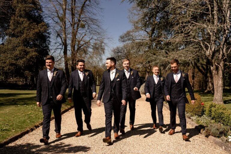 The groom and groom's men walk along the gravel track towards the hotel