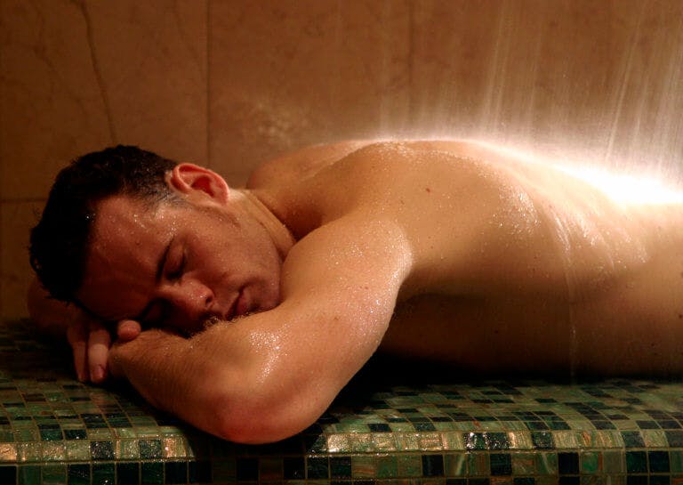 A male lying on a tiled hammam bed enjoying a spa treatment at SenSpa.