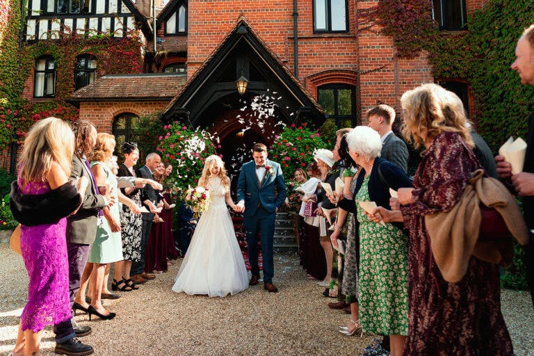 The Bride and Groom smile whilst confetti is thrown