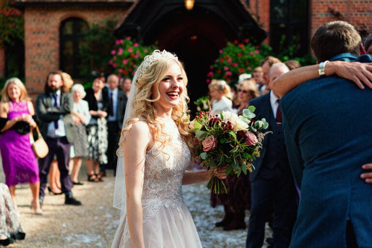 The bride smiles as she holds her bouquet outside the hotel