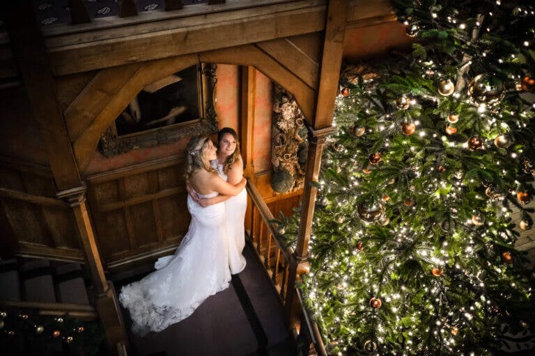 Hannah & Steph pose at the bottom of the staircase close to the Christmas tree