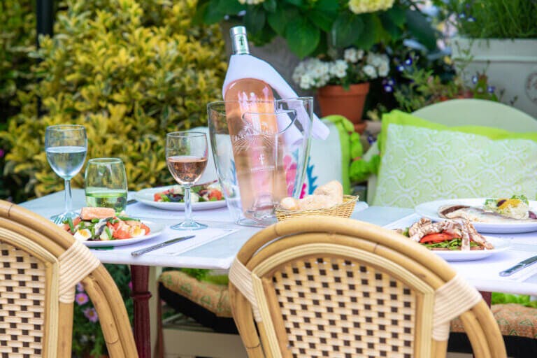 Table set for dining outside in summer with large bottle of rose wine on ice