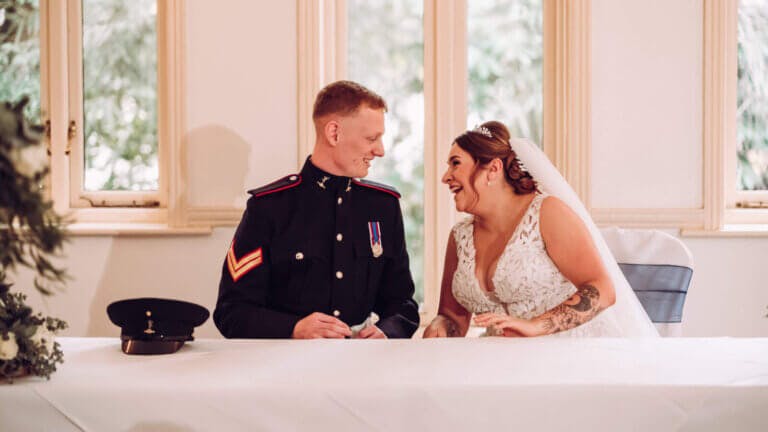 The couple smile at each other before signing the register