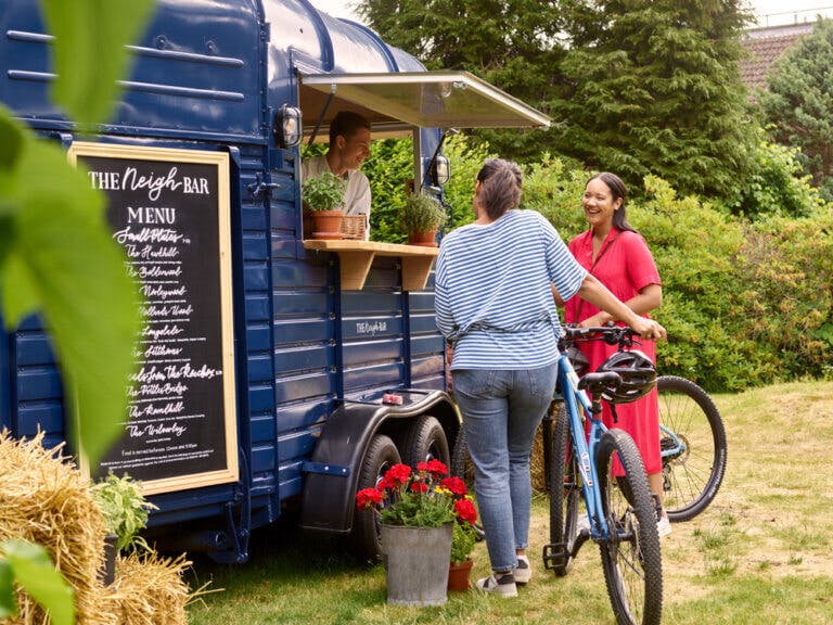 Two women ordering food and drinks at an outdoor bar