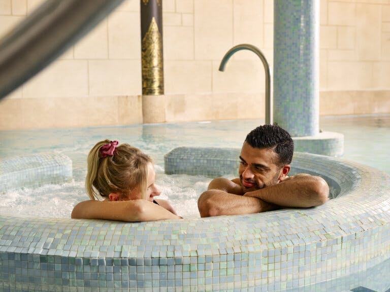 Man & woman relaxing in the hydro pool at the spa, leant on the volcano.