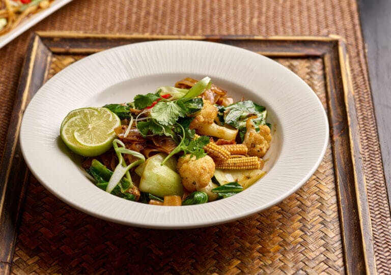 Vegetarian noodle dish with cauliflower, baby corn, pak choi, lime and more, served on rattan tray at Zen Garden Restaurant, Brockenhurst