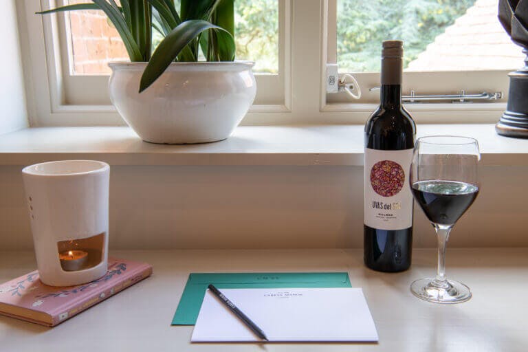 Bedroom table details - note pad, pencil, glass of wine at Careys Manor Hotel