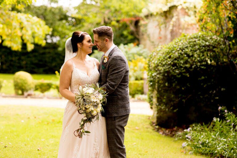Bride and groom stare lovingly at each other on wedding day at Careys Manor hotel in green gardens