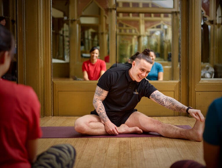 Two SenSpa members stretching in the fitness studio with SenSpa personal trainer leading the class. Girls' retreat.
