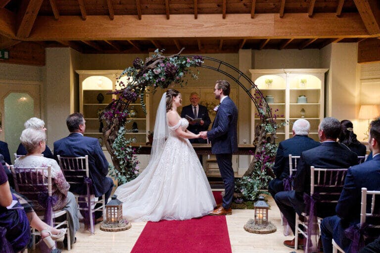 Bride & Groom stand looking at each other during the wedding ceremony in front of a moon arch