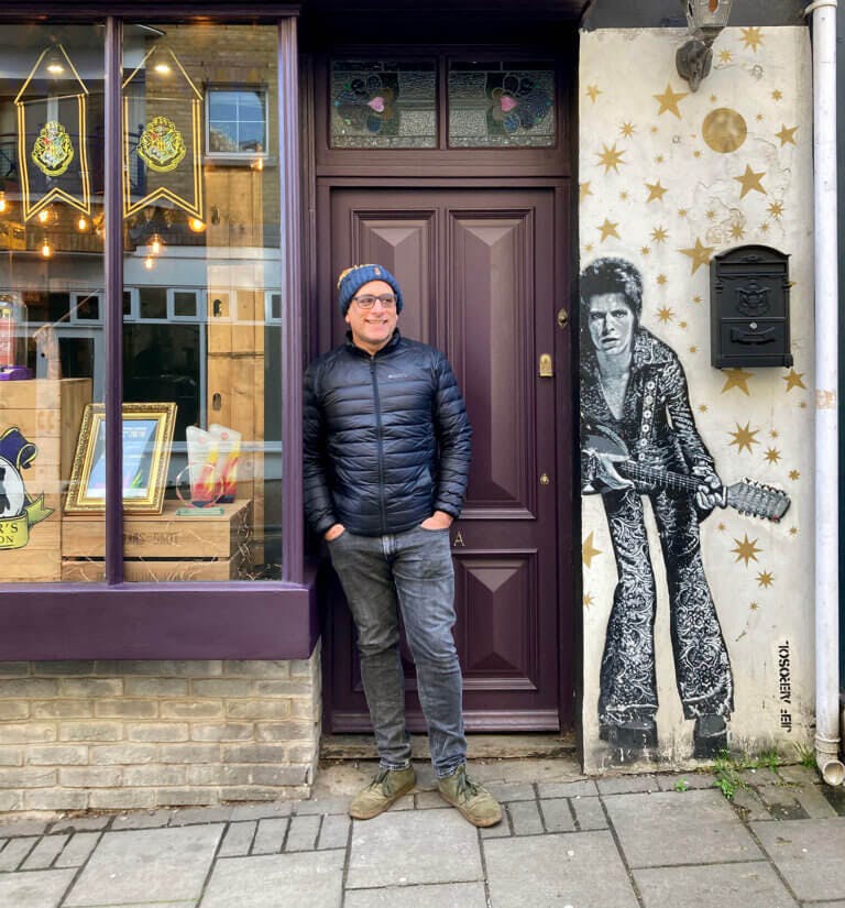 Wedding photographer Az Rehman poses next to David Bowie wall art