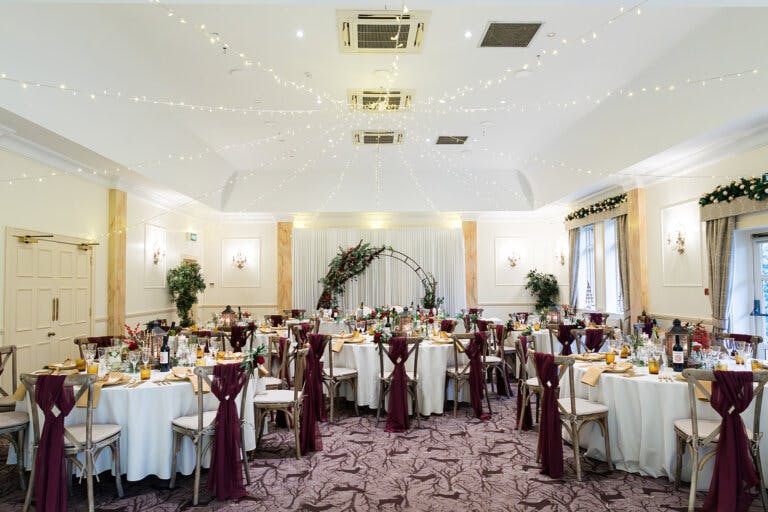 The Cedar Suite set for the wedding breakfast with red sashes on the chairs and the moon arch in the distance