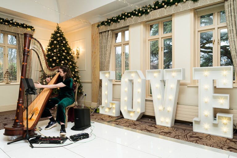 Harpist plays on a white dancefloor in front of large letters spelling love.