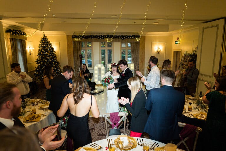 Guests clap as the bride and groom enter the wedding breakfast