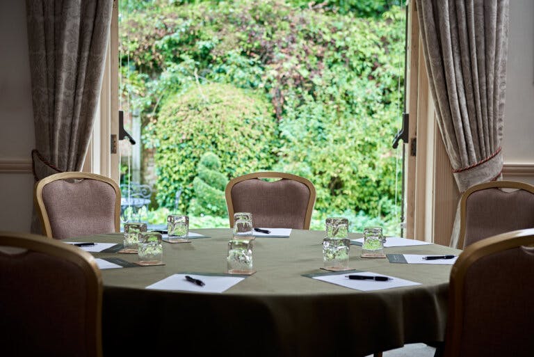 View to the Cedar garden with a table set for a meeting room in the foreground