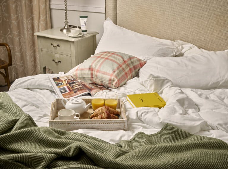 breakfast tray led on an unmade bed with a positive planner and magazines also on the bed | New Forest Hotel Careys Manor Hotel & SenSpa