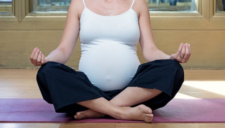 Pregnant lady posing in a lotus pose.