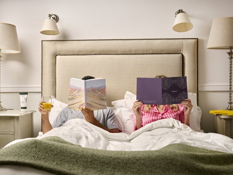Couple lie in bed with magazines covering their faces