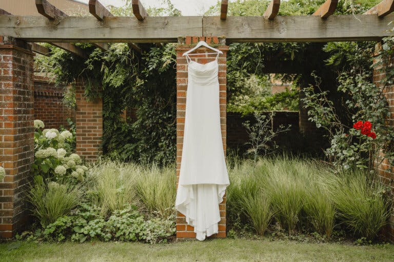 Wedding dress hanging in the garden surrounded by plants and flowers