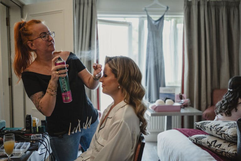 The bride prepares for the ceremony with the hairdresser