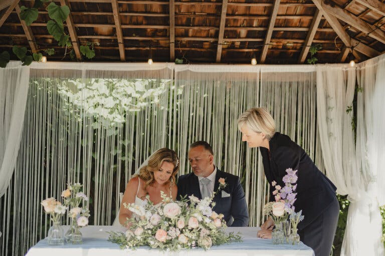 The bride and groom sign the register as the registrar looks on