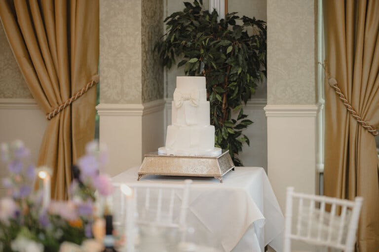 White wedding cake shown on the cake table