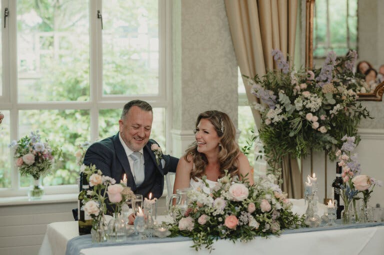 Bride and Groom laugh together on the Top table