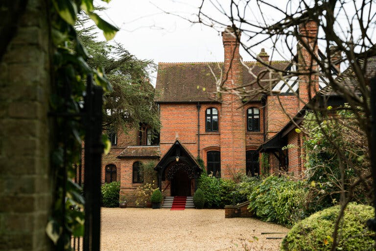Front shot of Careys Manor Hotel in winter, showing a red carpet at the main entrance with a lit garland around the top of the door.