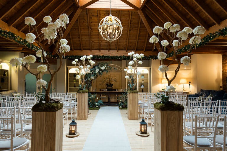 Image shows a white carpet down a central aisle with tall plinths and floral arrangements on either side