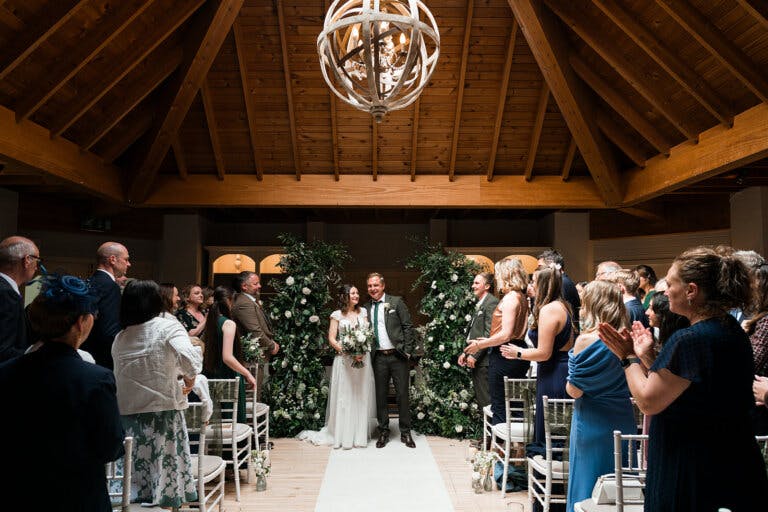 The Bride and her father walk arm-in-arm down the aisle