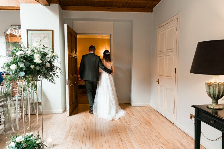 The bride and groom leave the ceremony room. The grooms arm is around the bride