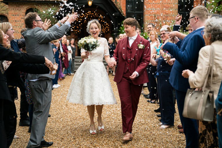Lily & Lottie walk hand in hand outside the entrance of the hotel whilst guests thro confetti
